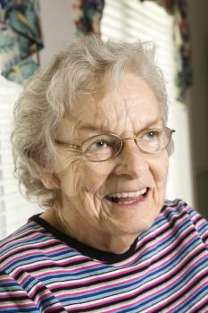 Portrait of elderly woman in eyeglasses smiling. Vertical shot.