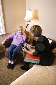 Nurse checking an elderly woman's blood pressure in assisted living home. Vertical shot.
