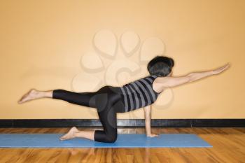 Woman at the gym practices yoga with one outstretched arm and leg. Horizontal shot.