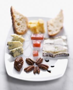 Appetizer tray with a selection of breads, cheeses, fruits and nuts. Vertical shot.
