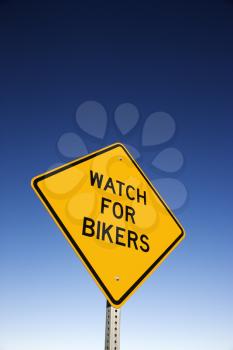 'Watch for Bikers' road warning sign and blue sky. Vertical shot.