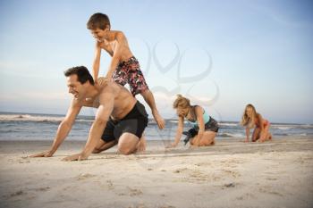 Family at the beach playing leap frog. Horizontal shot.