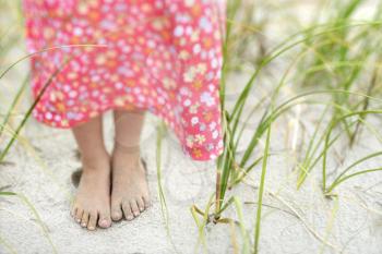 Closeup of a little girl's barefoot feet that are covered in sand. Horizontal shot.