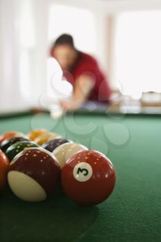 Selective focus shot of racked pool balls in foreground as a man is about to break. Vertical shot.