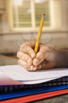 Child's hand holding pencil doing homework. Vertically framed shot.