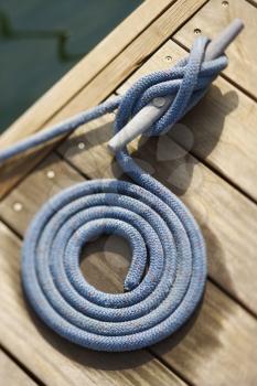 Coiled rope tied to docking cleat. Vertically framed shot.