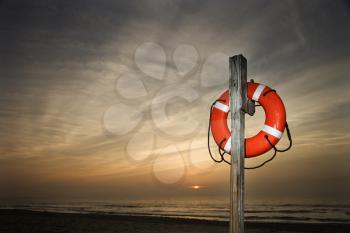 Life Preserver on pole at beach at sunset.  Horizontally framed shot.