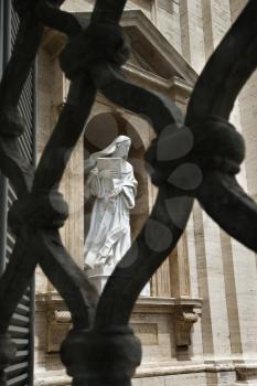 Statue of Saint Teresa of Avila seen through opening in iron fence. Vertical shot.