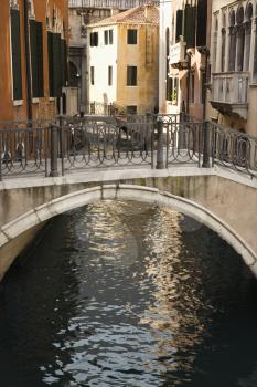 Canal and walking bridge surrounded by Old World buildings in Venice, Italy. Vertical shot.