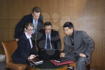 Ethnically diverse group of businessmen and a businesswoman look at a laptop computer screen. Horizontal shot.