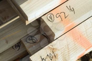 Closeup of the ends of building timber. Their lengths have been written in marker. Horizontal shot.