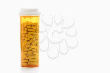 Yellow pill bottle filled with tablets against a white background. Horizontal shot. Isolated on white.