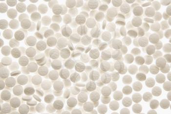 Pile of white round white pills on a white backlit background. Horizontal shot. Isolated on white.