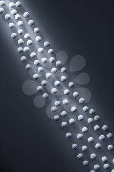 Overview of white round pills illuminated by a shaft of light. Vertical shot.