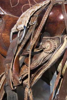 Detail of a western style horse saddle and cinch on a rail. Vertical shot.