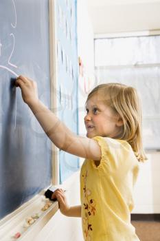 Young female student doing math on blackboard. Vertically framed shot.