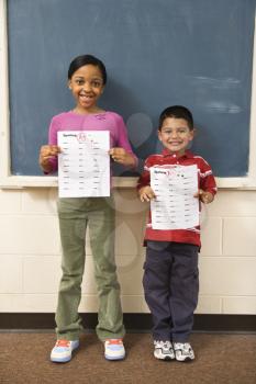 Young students holding spelling tests with good grades. Vertically framed shot.