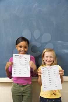 Young students holding spelling tests with good grades. Vertically framed shot.