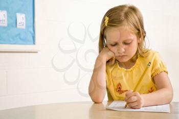 Young girl in classroom writing on paper. Horizontally framed shot.