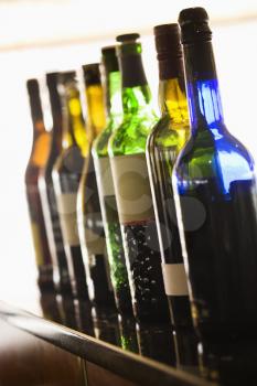 Tilted view of a row of assorted colorful wine bottles. Vertical shot.