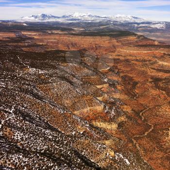 Aerial view of a of rural, desert landscape with mountains in the background and some snow scattered on the ground. Square shot.