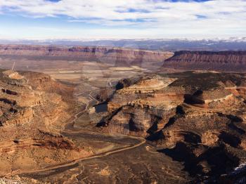 Aerial view of an arid, craggy landscape with canyons. Horizontal shot.