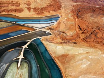 Aerial view of an arid, craggy landscape surrounding tailing ponds. Horizontal shot.