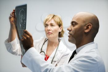Male and female physicians holding and looking at patient xray film.
