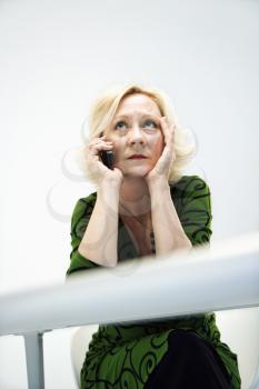 Caucasian middle aged businesswoman in office on cellphone looking stressed and upset.