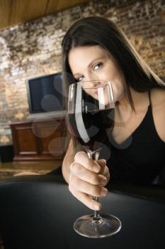 Pretty young Caucasian woman toasting wine glass and smiling.