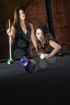 Two attractive young women playing pool.