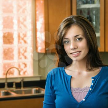 Pretty Caucasian young woman smiling in kitchen.