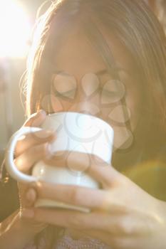 Young Caucasian woman drinking from coffee cup.
