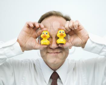 Portrait of middle aged  Caucasian businessman holding rubber ducks up to face.