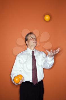 Caucasian middle aged businessman juggling oranges.