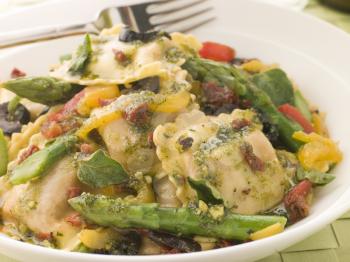 Royalty Free Photo of Roasted Vegetable Ravioli with Pesto Dressing Sun Blushed Tomatoes and Asparagus