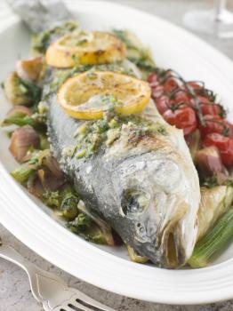 Royalty Free Photo of Whole Roasted Sea Bass with Fennel Lemon Cherry Vine Tomatoes and Salsa Verde
