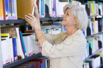 Royalty Free Photo of a Woman Taking a Book Off a Shelf in a Library
