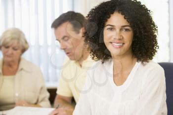 Royalty Free Photo of a Woman at a Study Table With a Man and Woman in the Background
