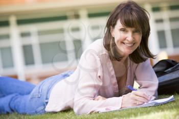 Royalty Free Photo of an Adult Woman Lying on Grass Writing in a Book