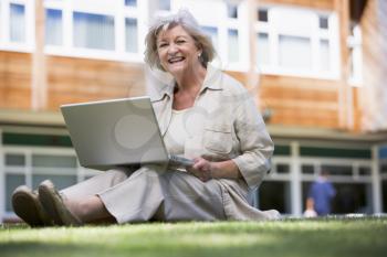 Royalty Free Photo of an Older Woman Sitting on the Lawn With a Laptop