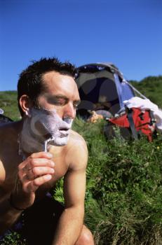 Royalty Free Photo of a Man Shaving at a Campsite
