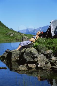 Royalty Free Photo of a Woman Relaxing by a Lake at a Campsite