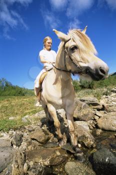 Royalty Free Photo of a Woman Crossing a Stream on Horseback