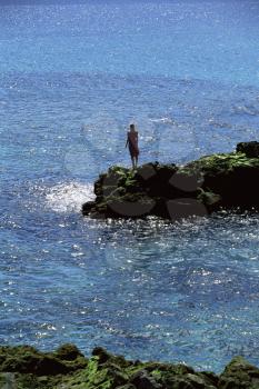 Royalty Free Photo of a Woman Standing on Rocks at the Water's Edge