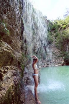 Royalty Free Photo of a Woman in a Bathing Suit By a Waterfall
