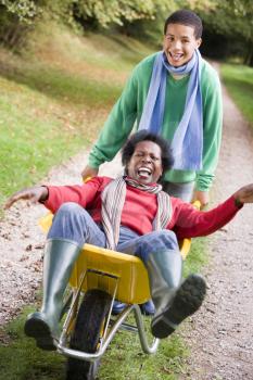 Royalty Free Photo of a Young Boy Pushing a Woman in a Wheelbarrow