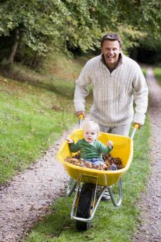 Royalty Free Photo of a Father Pushing a Baby in a Wheelbarrow