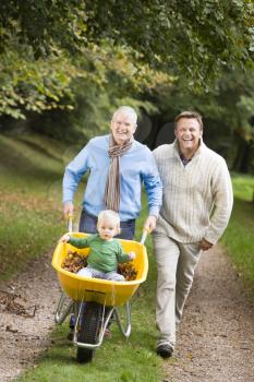 Royalty Free Photo of Two Men Pushing a Baby in a Wheelbarrow on a Trail