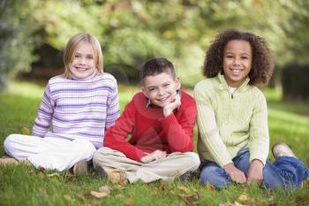Royalty Free Photo of Three Children Sitting in a Park